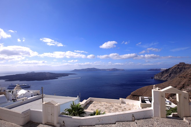 Con đường ven bờ đ&ocirc;ng đảo, nối giữa Fira v&agrave; Imerovigli c&ograve;n đẹp hơn những g&igrave; ta thấy tr&ecirc;n tranh ảnh: sơn trắng, rải sỏi, chỉ d&agrave;nh cho người đi bộ, chiều ngang chừng hai m&eacute;t rưỡi, v&agrave; nối với những căn nh&agrave; b&aacute;m v&agrave;o v&aacute;ch n&uacute;i, với c&aacute;c bậc cầu thang, cổng trắng v&agrave; qu&aacute;n c&agrave; ph&ecirc;.